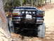 1989 Ford Bronco - Modified Ford F-Series truck with off-road modifications navigating a dirt trail.