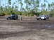 1989 Ford Bronco - Two off-road vehicles are stuck in the mud, with a person attempting to connect them with a tow strap.