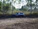 1989 Ford Bronco - Ford Bronco is stuck in the mud with trees in the background.