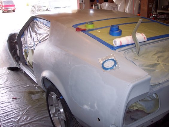 1971 Ford Mustang body in primer, prepped for paint with masking tape on the rear window