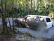 1989 Ford Bronco - A white 1989 Ford Bronco navigates a muddy trail, kicking up water and dirt.