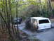 1989 Ford Bronco - A white Ford Bronco kicks up mud while driving through a wooded trail, with a Jeep parked nearby.