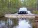 1988 Jeep Comanche - Jeep Cherokee XJ navigates a water crossing on a wooded trail.