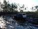 1989 Ford Bronco - A white 1989 Ford Bronco navigates a muddy track, its tires deep in the mire.