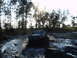 1989 Ford Bronco - A 1989 Ford Bronco navigates a muddy track surrounded by trees.