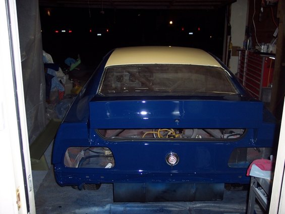 Rear view of a 1971 Ford Mustang undergoing repaint, showing blue body and cream roof