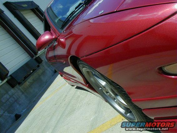 Red car side view, showing front wheel and fender