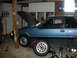 1990 Ford Mustang - A blue 1990 Ford Mustang coupe is shown in a garage with its hood open and suspension components laid out for service.