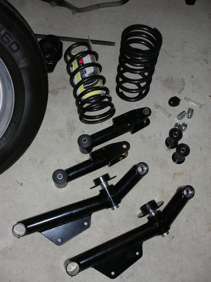 Black suspension control arms and coil springs on a concrete floor