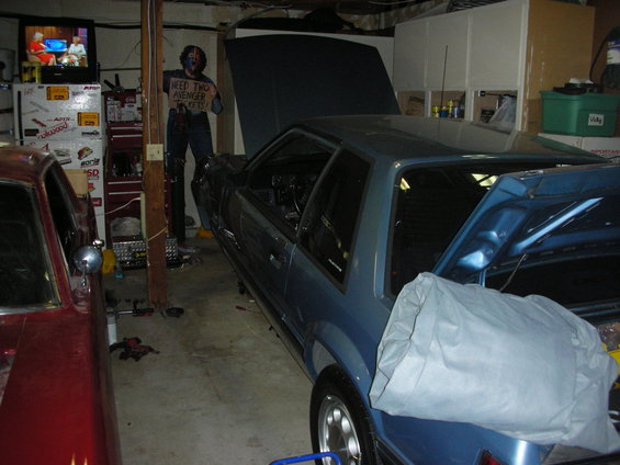 Blue 1990 Ford Mustang and red car in garage, hoods open