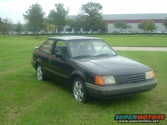 Dark 1989 Ford Escort coupe parked on grass, front 3/4 view
