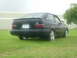 1989 Ford Escort - This black Ford Escort is seen from the rear, parked on a grassy area with a building in the background.
