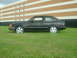 1989 Ford Escort - This dark-colored 1989 Ford Escort coupe is seen from the side, parked on a grassy area in front of a building.