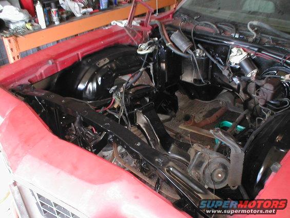 Red car's engine bay with black inner fenders and wiring visible