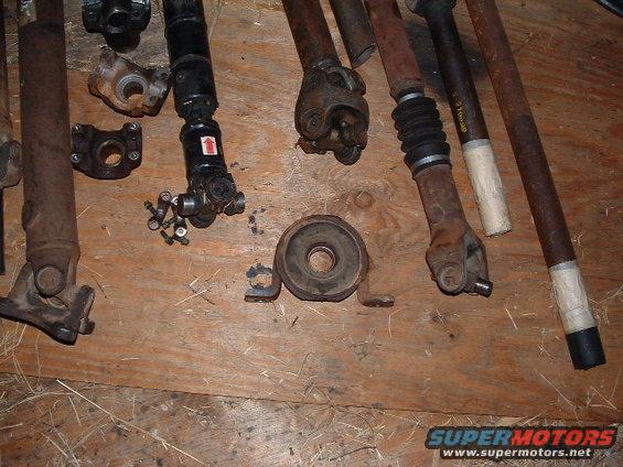Collection of rusty driveshafts and U-joints on a wooden surface