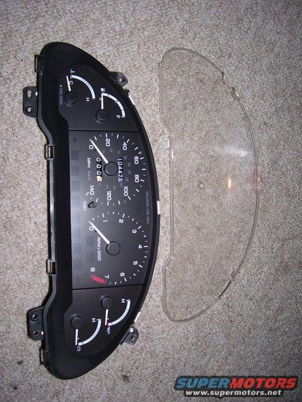 Car dashboard instrument cluster with clear plastic cover next to it