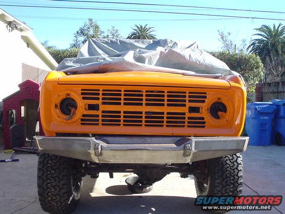 Orange 1977 Ford Bronco front end with a tarp over the roof