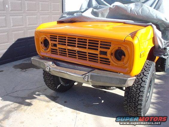 1977 Ford Bronco front end with orange paint, custom bumper, and cover on hood