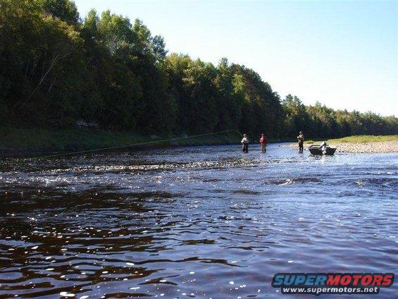 People fishing in a river with a boat