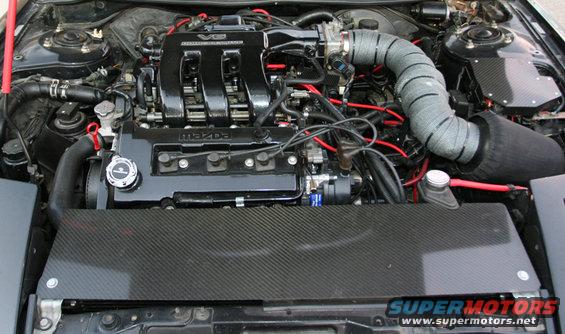 Mazda V6 engine bay with aftermarket intake and carbon fiber covers