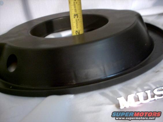 Black air cleaner housing with a yellow Stanley measuring tape inserted into the opening. 'MUS' emblem is visible in the lower right