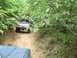 1989 GMC Jimmy - Two off-road vehicles navigate a wooded trail.