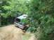 1989 GMC Jimmy - An off-road vehicle navigates a rough, wooded trail.