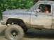 1989 GMC Jimmy - This muddy pickup truck appears to be off-roading, with dirt covering its exterior.