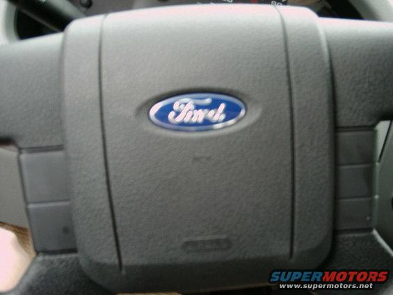 Ford steering wheel with blue oval logo. Part of dashboard visible