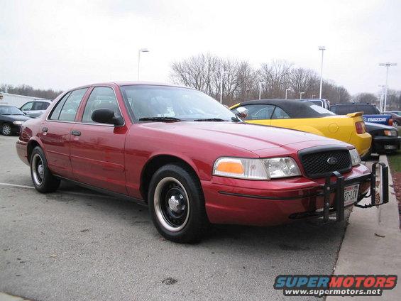 Red 2001 Ford Crown Victoria sedan with a push bar, parked on asphalt