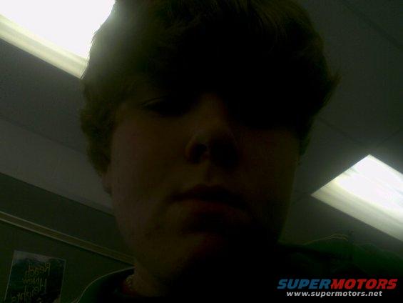 Person's face in shadow, with overhead lights and a poster on the wall