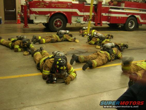 Fire truck with text 'VOL. FIRE CO. NO. 1 GRILL, PA' and firefighters lying on the floor