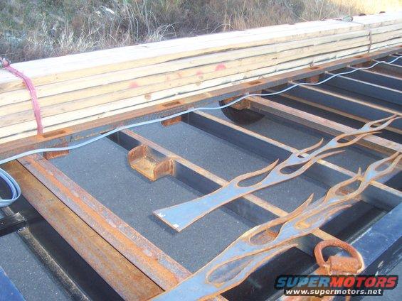 spare tire mounts on crossmember at front of trailer. Frame is tall enoufgh to have tire completly hidden when hanging under trailer
