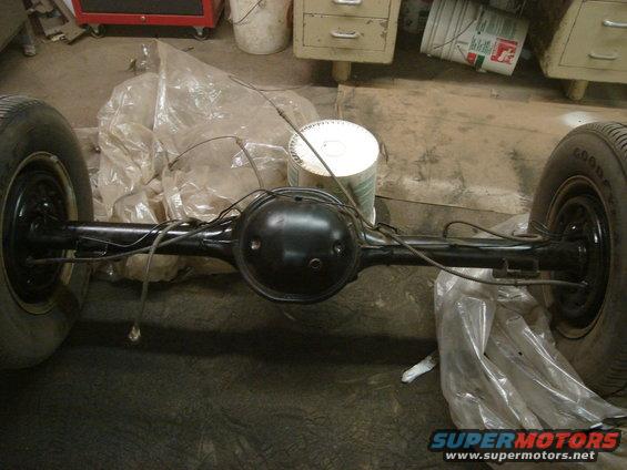 Rear axle assembly with two wheels, covered in plastic sheeting, in a garage setting