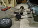 1992 Ford Crown Victoria - Rear axle assembly and leaf springs are laid out on the floor next to a tire and a jack, suggesting a vehicle repair or restoration project.