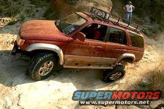Red 1996 Toyota 4Runner with roof rack driving on a dirt trail, front passenger side visible