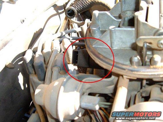 Close-up of a black electrical connector plugged into a carburetor
