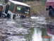 1995 Dodge 1500 - A brown Jeep Wrangler TJ is partially submerged in murky water, with a red truck visible on the right side of the frame.