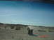 1996 Ford Bronco - A convoy of Jeep Wranglers travels through a dusty desert terrain under a clear blue sky.