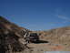 1996 Ford Bronco - Several SUVs, including a 1996 Ford Bronco, travel a dusty path through a rocky desert landscape.