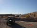 1996 Ford Bronco - Several off-road vehicles traverse a dusty, rocky terrain under a clear blue sky.