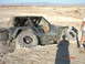 1996 Ford Bronco - A Jeep Wrangler is stuck in the dirt, with its large tires digging into the terrain.