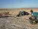 1996 Ford Bronco - A black Ford Bronco is stuck in a deep sandy ditch, with a teal Jeep attempting to pull it out in a desert environment.