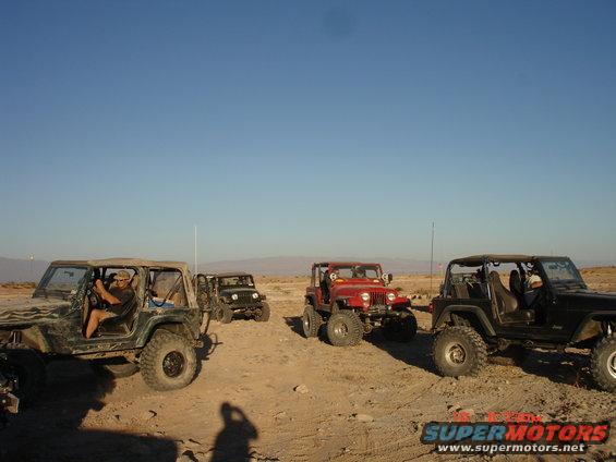 Four Jeeps parked in a desert with mountains in the background
