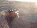 1996 Ford Bronco - A red off-road vehicle navigates a challenging dirt path in a sun-drenched desert landscape.