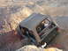 1996 Ford Bronco - A Jeep Wrangler is stuck in a deep ditch off-road, with its tires digging into the dirt.