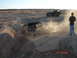 1996 Ford Bronco - Two Jeeps tackle a challenging off-road course, kicking up dust as one navigates a steep drop.