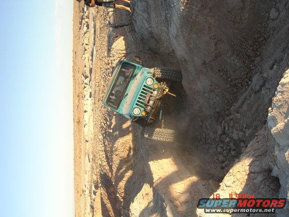 Teal Jeep CJ-7 with winch, tilted on a dirt incline