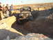 1996 Ford Bronco - A Jeep Wrangler maneuvers through a deep dirt trench in an off-road landscape.