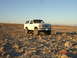 1996 Ford Bronco - A white Ford Bronco is parked in a desert landscape with mountains in the background.